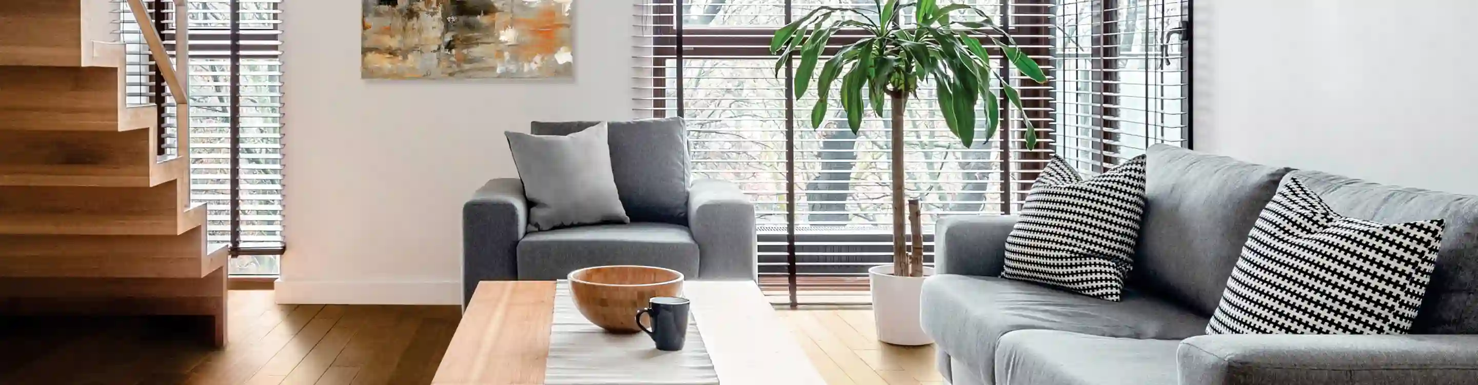 wood look brown blinds custome window treatments in living area with grey sofa and armchair on light hardwood flooring